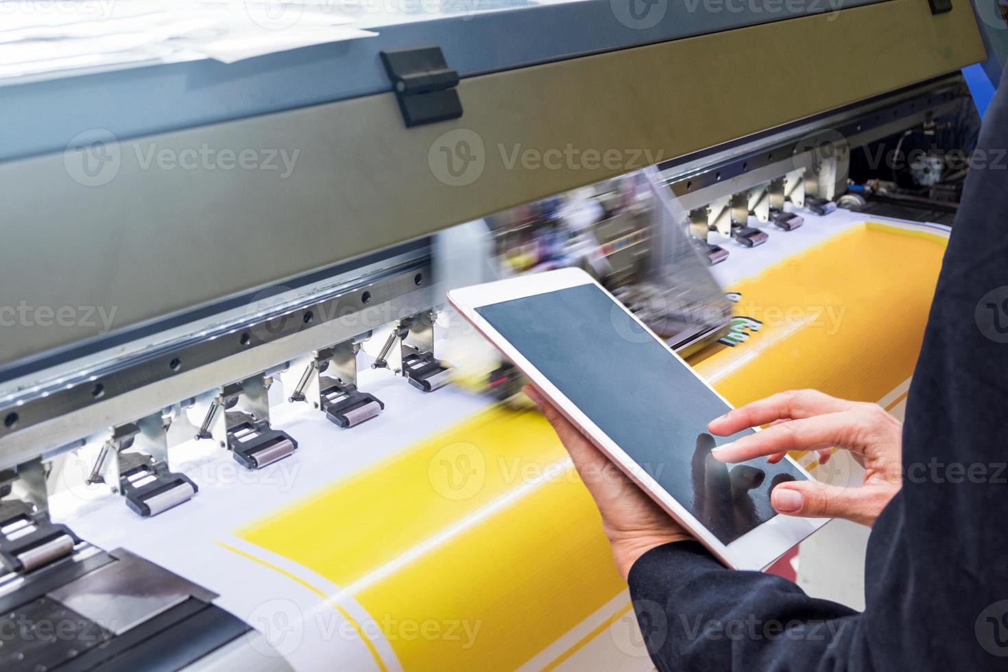 tablet con controllo tattile tecnico su stampante a getto d'inchiostro formato durante vinile giallo foto