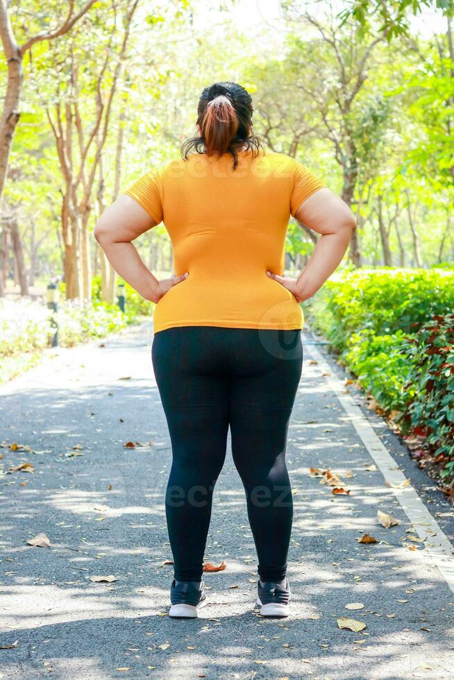 Grasso asiatico donna indossare un' giallo camicia mattina esercizio nel il parco. il concetto di peso perdita. esercizio per bene Salute di obeso le persone. foto