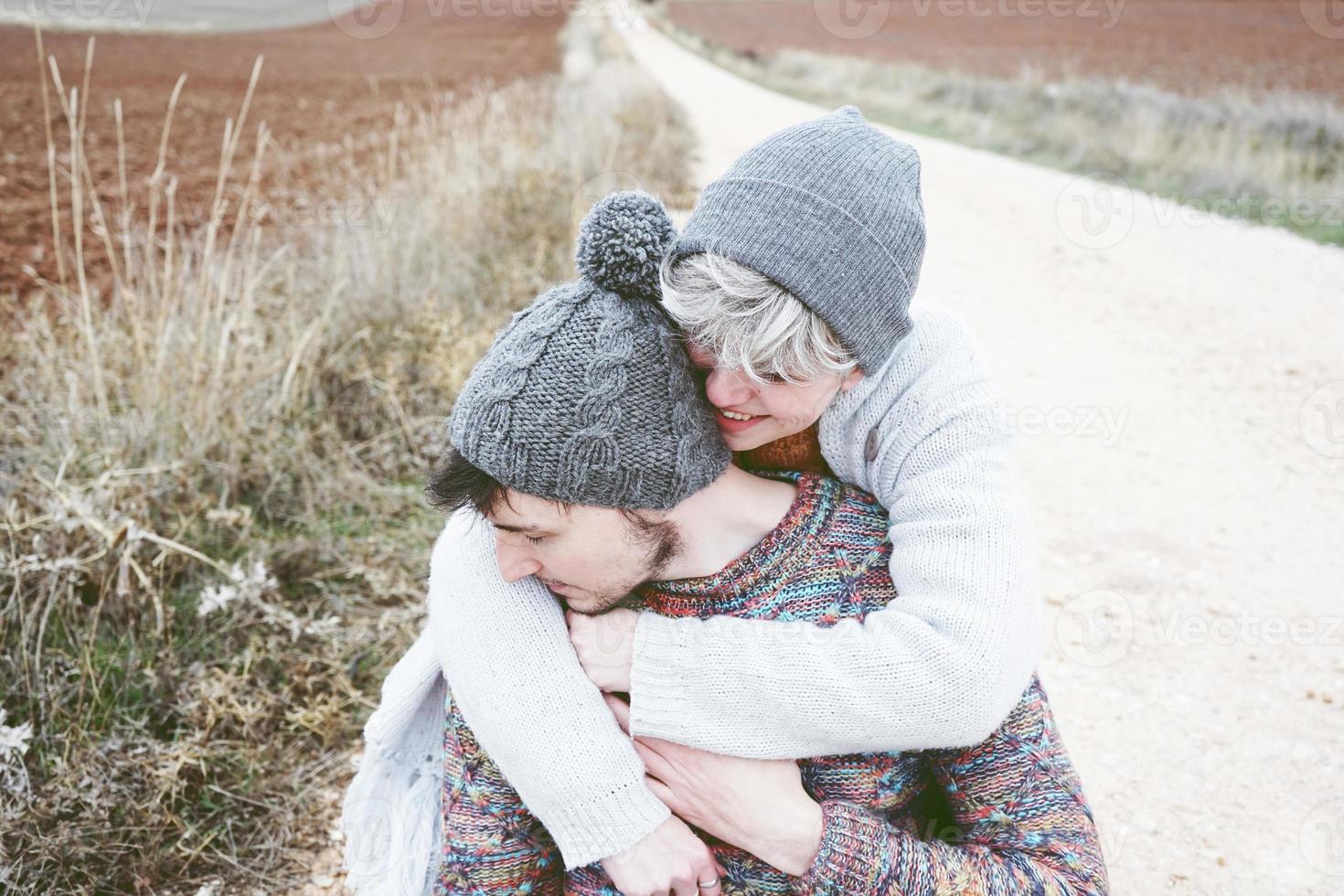 coppia di giovani millennial che si abbracciano e sorridono in un viaggio avventuroso su un sentiero di campagna all'aperto foto