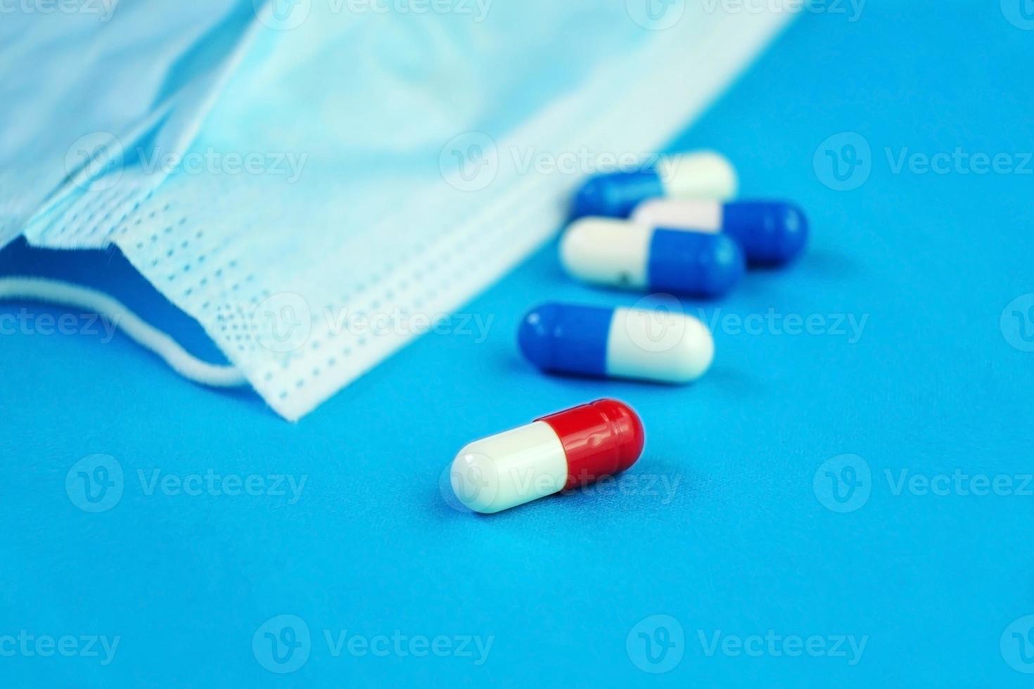 una macro dettagliata di pillole e capsule su una maschera medica con sfondo blu foto