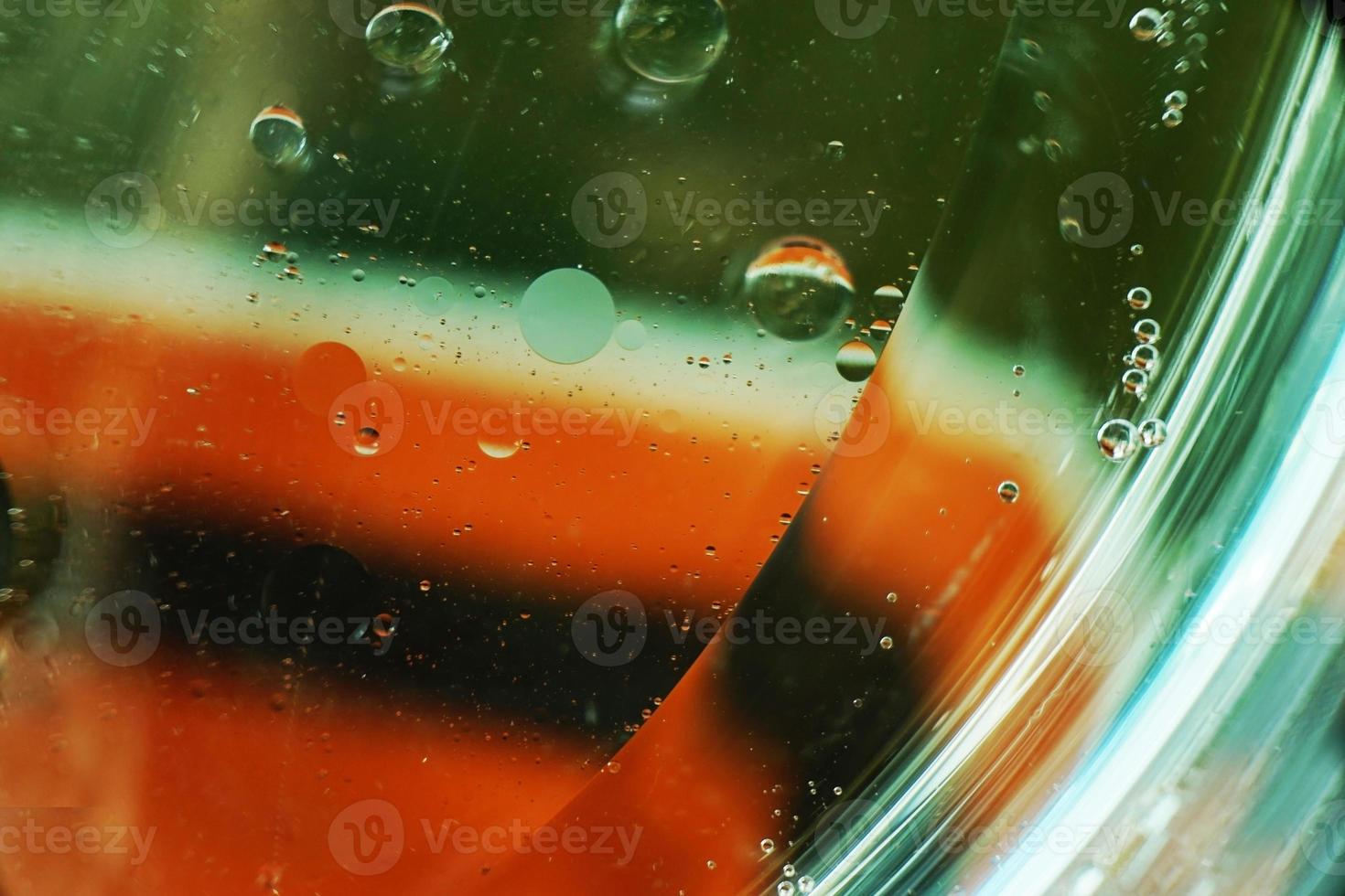 una bella e colorata macro di bolle d'olio sull'acqua con una trama a strisce bianche, verdi e rosse come motivo di sfondo con filtro vintage foto