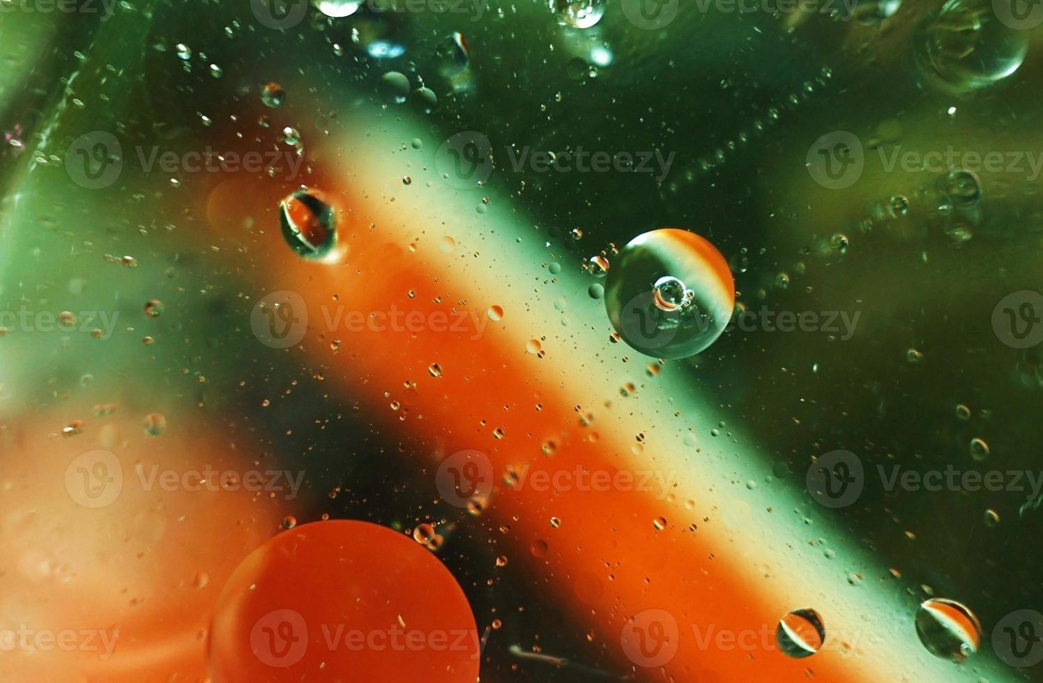 una bella e colorata macro di bolle d'olio sull'acqua con una trama a strisce bianche, verdi e rosse come motivo di sfondo con filtro vintage foto