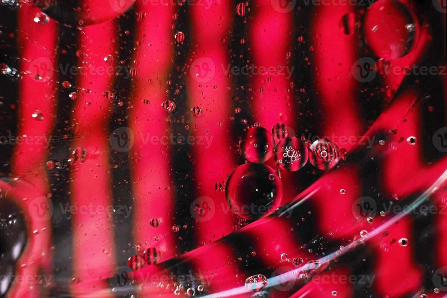 una bella e colorata macro vibrante di bolle d'olio sull'acqua con un contrasto rosa e nero come trama a strisce e motivo di sfondo foto