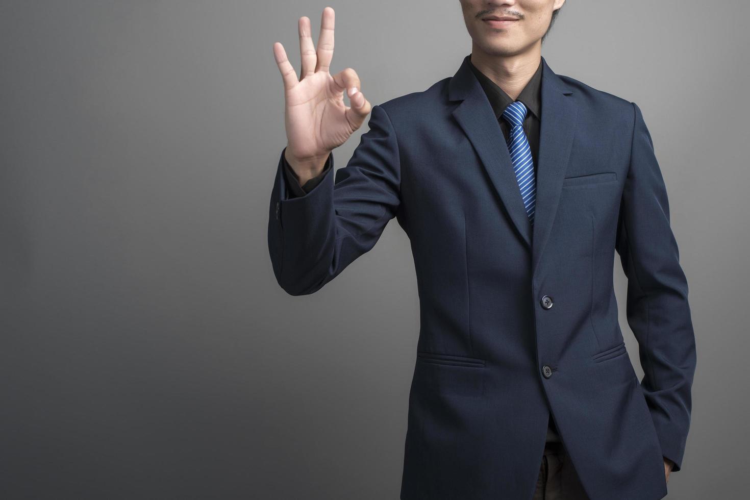 primo piano di uomo d'affari in abito blu mano ok su sfondo grigio foto