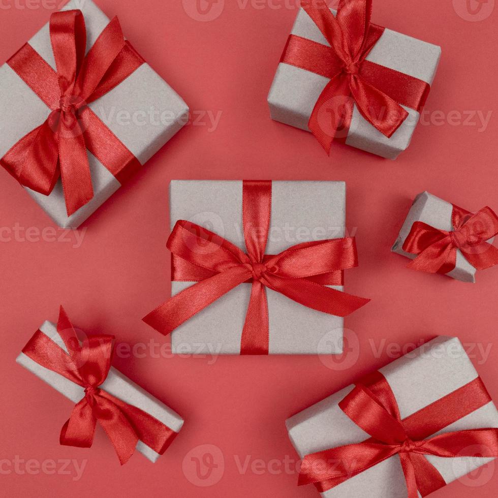 scatole regalo avvolte in carta artigianale con nastri e fiocchi rossi. festivo piatto monocromatico. foto