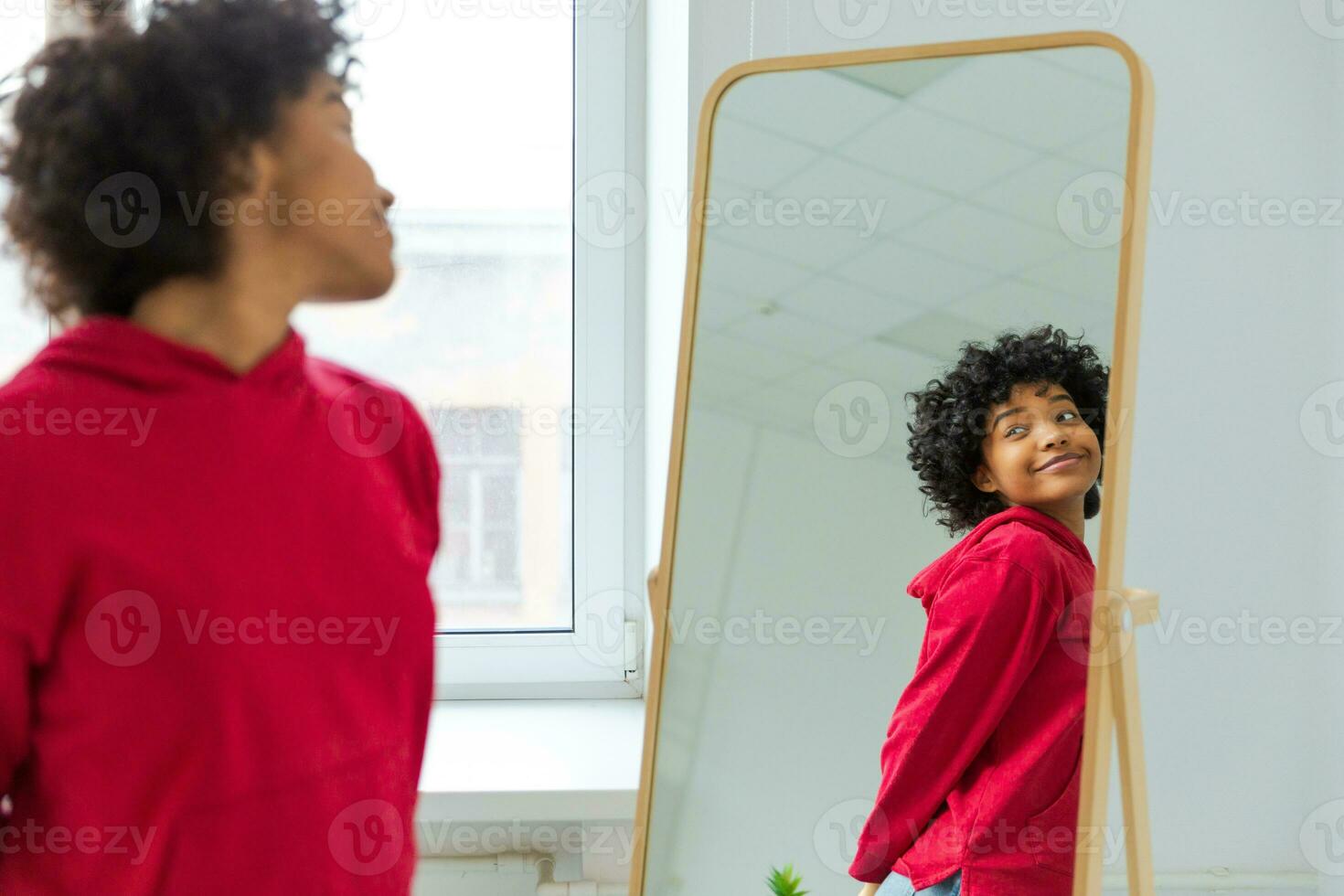 amore te stesso. bellissimo giovane sorridente africano americano donna danza godendo sua specchio riflessione. nero signora guardare a specchio guardare fiducioso e contento. se stesso amore concetto. foto
