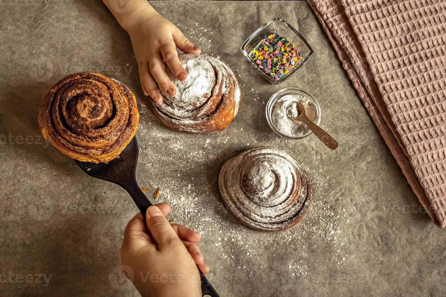 la mano dei bambini prende un panino alla cannella appena sfornato foto