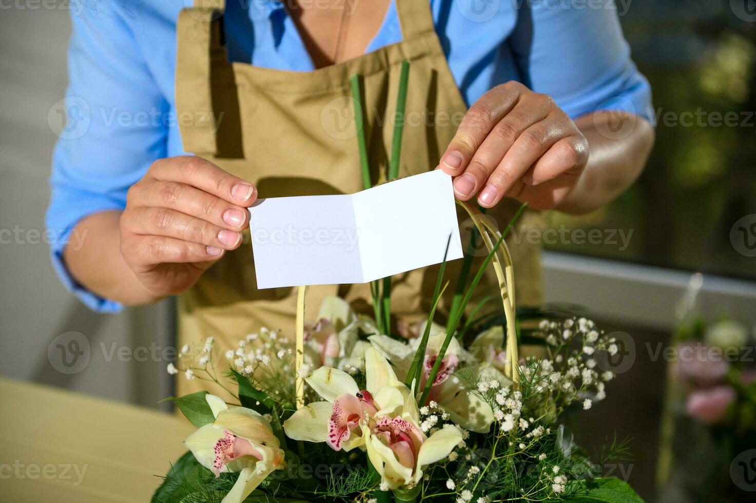 avvicinamento femmina fioraio Tenere bianca vuoto congratulazioni carta al di sopra di un' carino fiore preparativi nel un' di vimini cestino foto