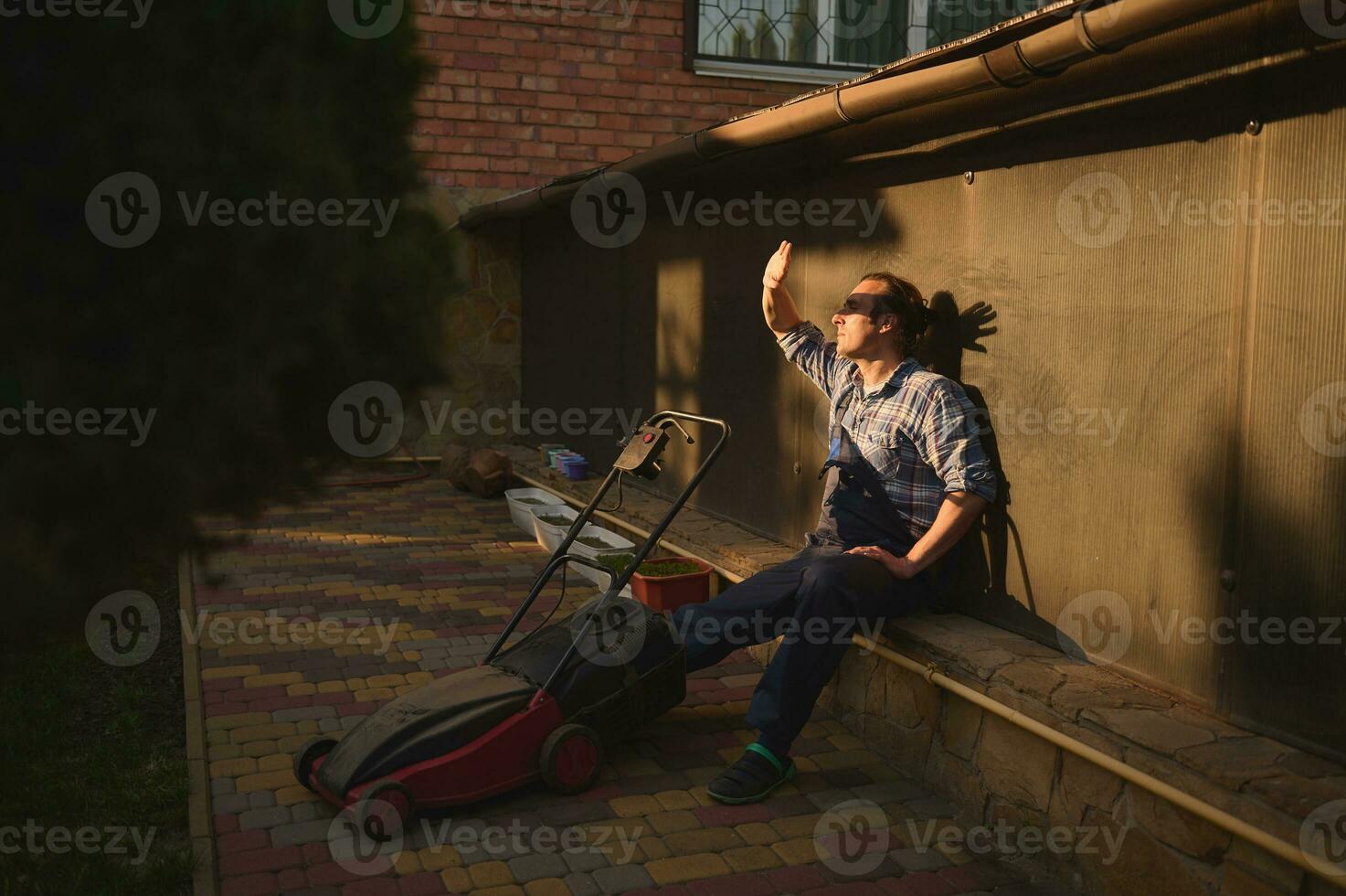 ritratto di un' lavoratore guardare a tramonto dopo finitura difficile Lavorando giorno nel giardino, rilassante all'aperto vicino un' prato falciatore foto