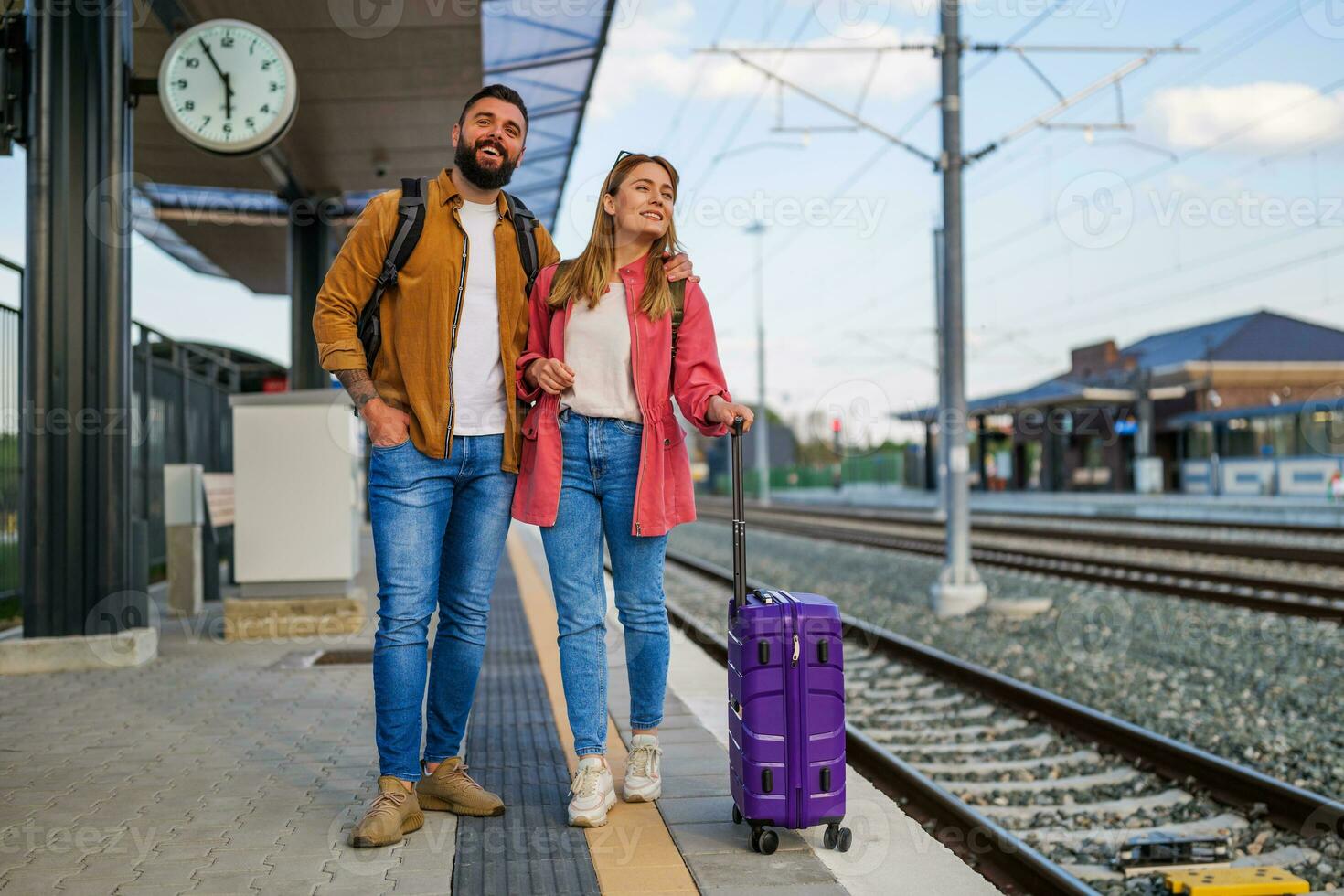 contento coppia è in piedi a ferrovia stazione e in attesa per arrivo di loro treno. foto