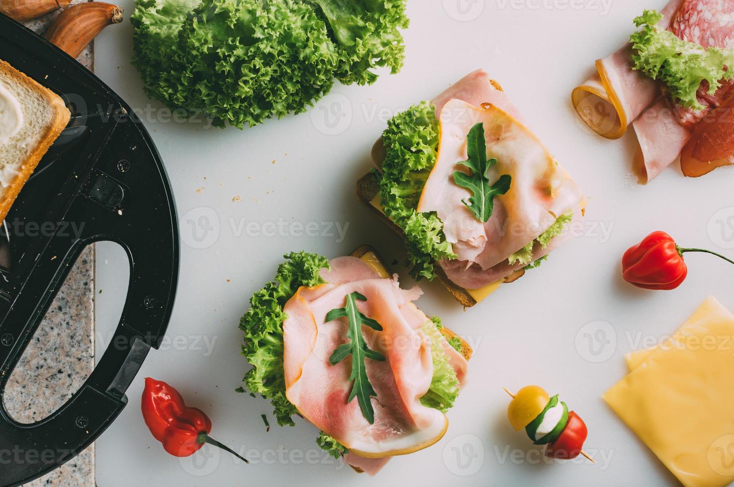 club sandwich con prosciutto, salame, manzo affumicato, formaggio, lattuga e rucola. preparazione del toast sandwich. vista dall'alto. foto