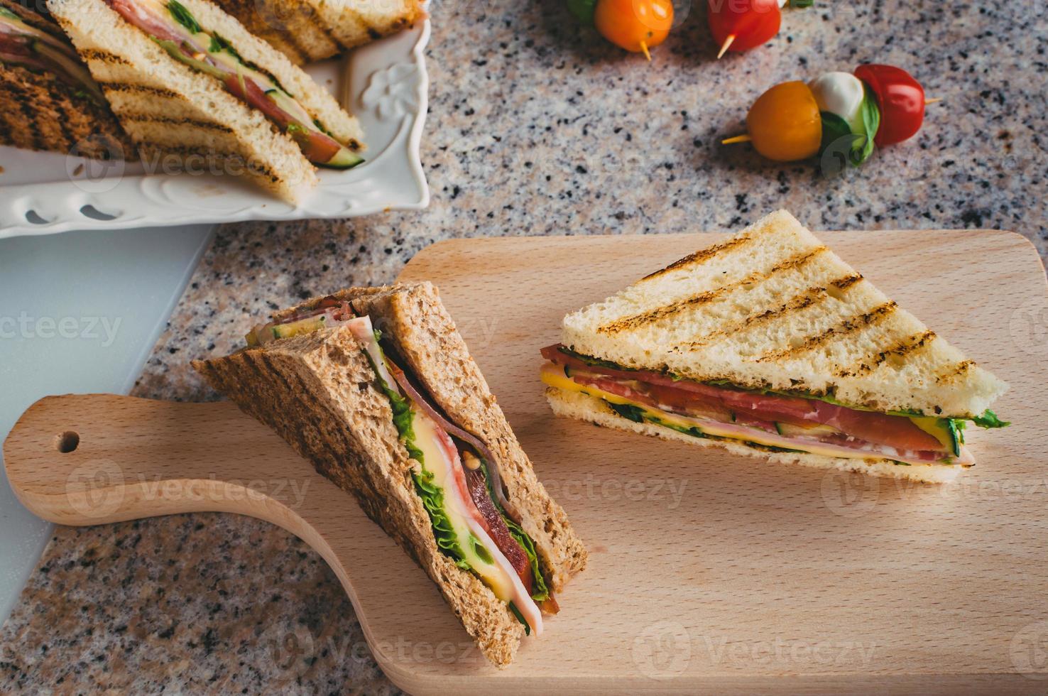 club sandwich con prosciutto, salame, manzo affumicato, formaggio, lattuga e rucola.preparazione di sandwich toast. foto