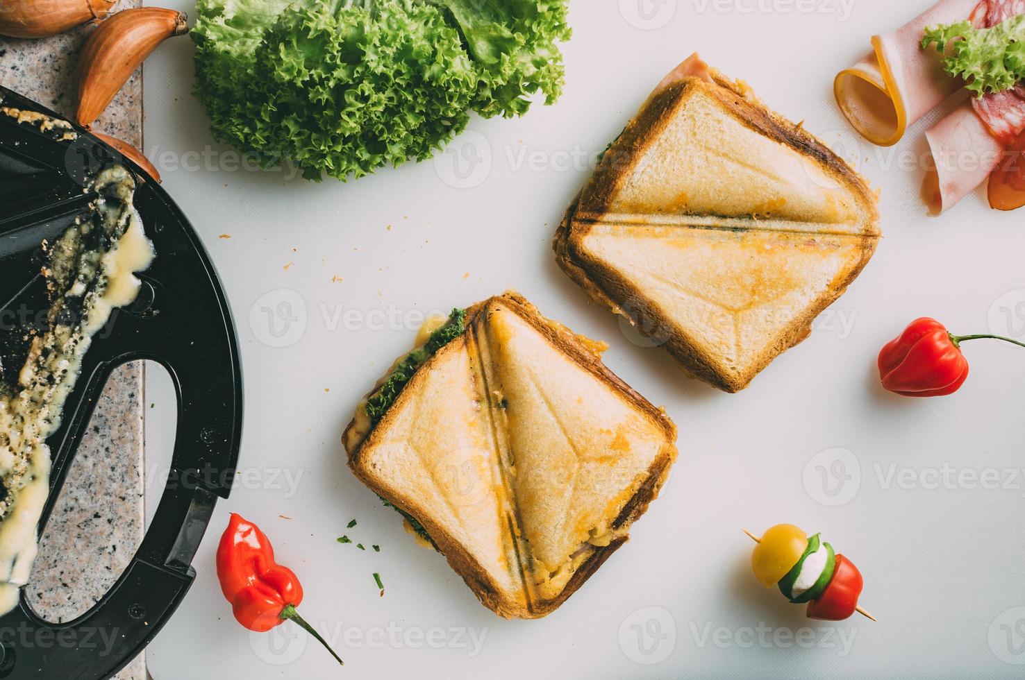 club sandwich con prosciutto, salame, manzo affumicato, formaggio, lattuga e rucola. preparazione del toast sandwich. vista dall'alto. foto