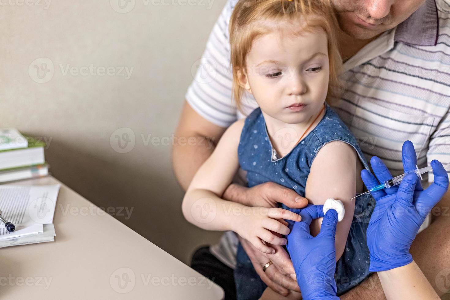 una bambina con suo padre nell'ambulatorio della clinica viene vaccinata contro il coronavirus.il concetto di vaccinazione, immunizzazione, prevenzione contro covid-19. foto