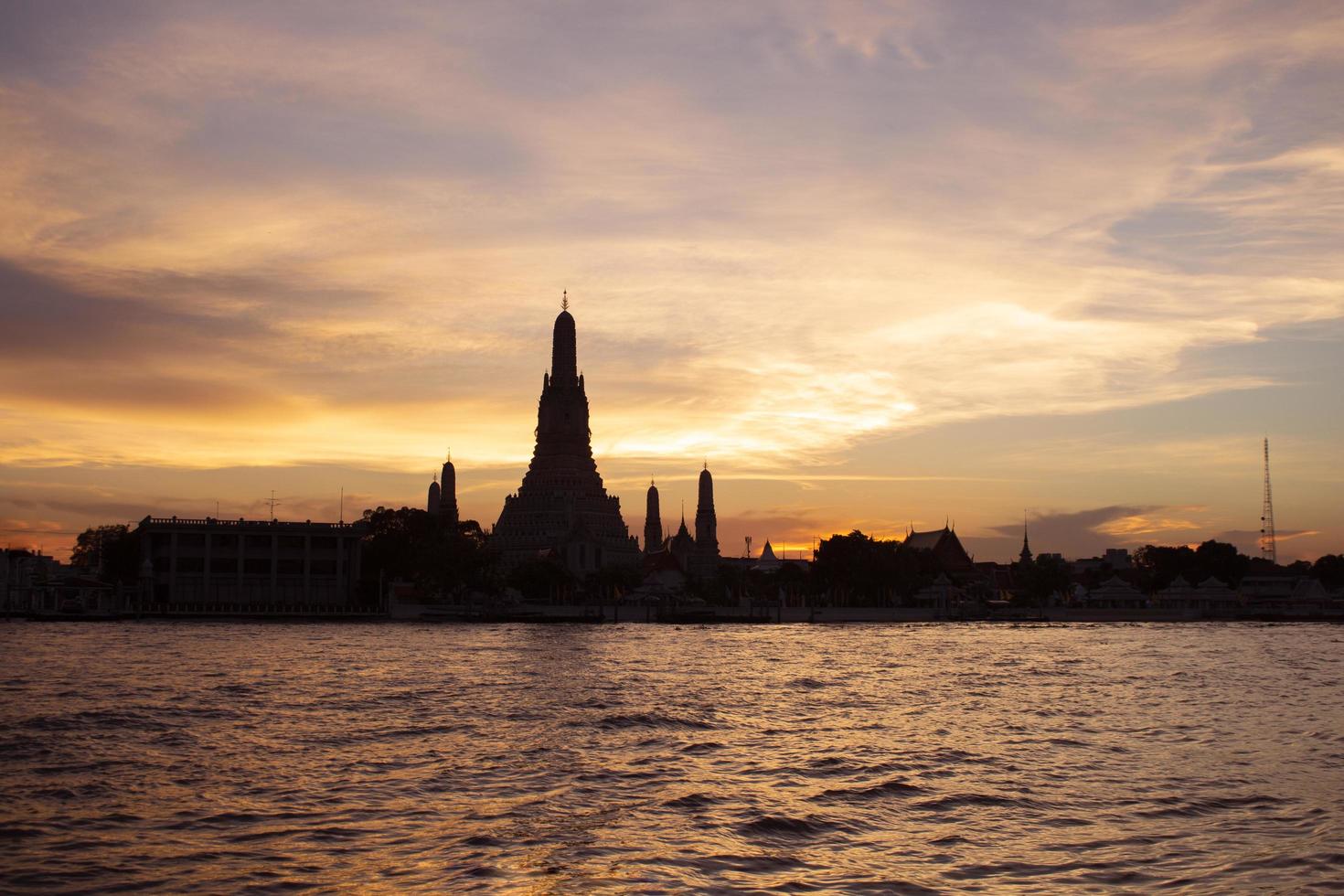 silhouette del tempio di wat arun al tramonto sul fiume chao phraya punto di riferimento di bangkok thailandia foto