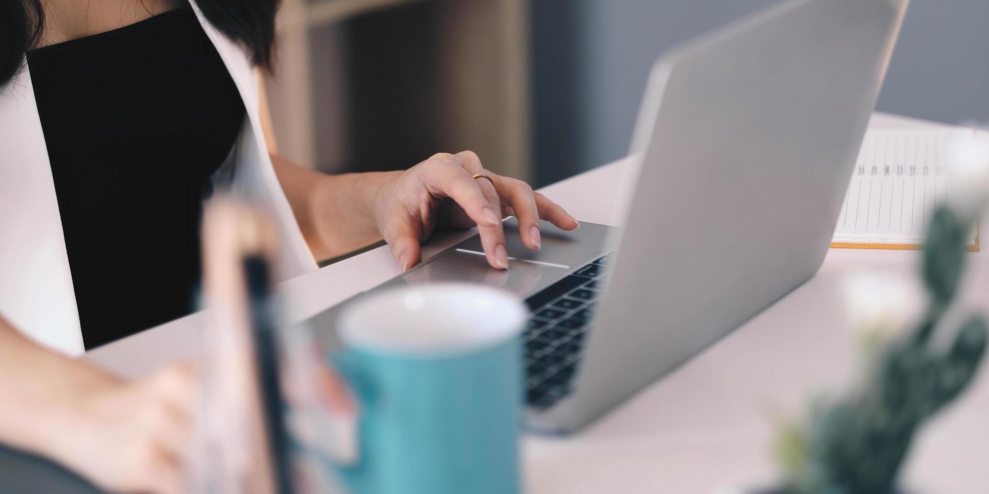 primo piano di mani femminili che digitano sulla tastiera di un computer portatile a casa in ufficio foto