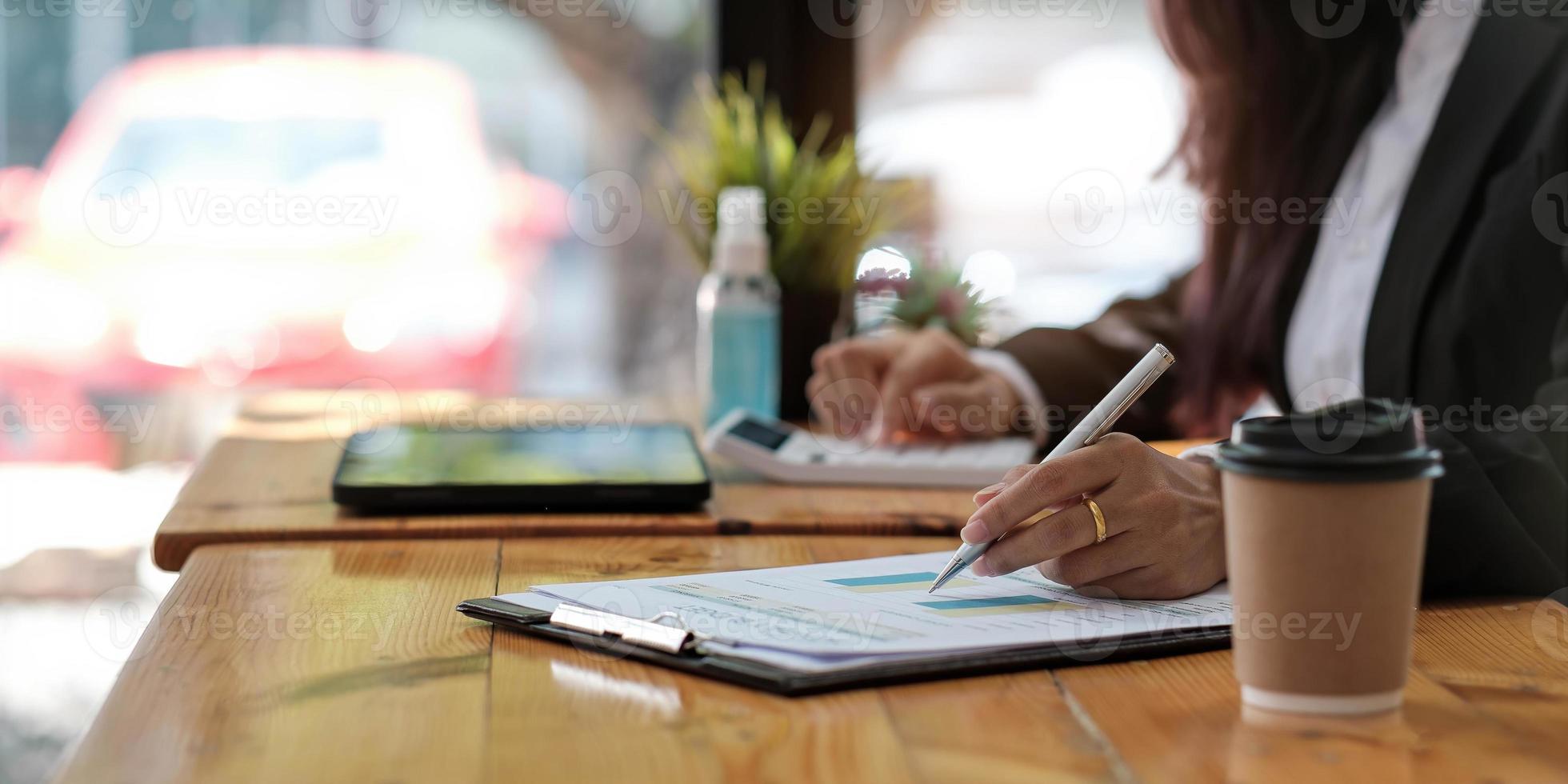 donna d'affari che utilizza la calcolatrice per fare finanza matematica sulla scrivania di legno in ufficio e lavoro aziendale sfondo, tasse, contabilità, statistiche e concetto di ricerca analitica foto