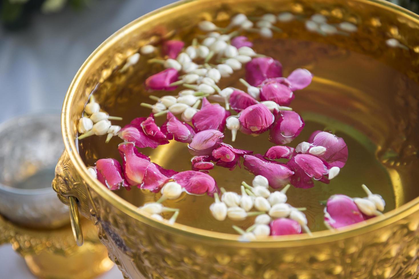 acqua nel mestolo d'acqua con piedistallo di fiori colorati per il festival di songkran, tailandia foto