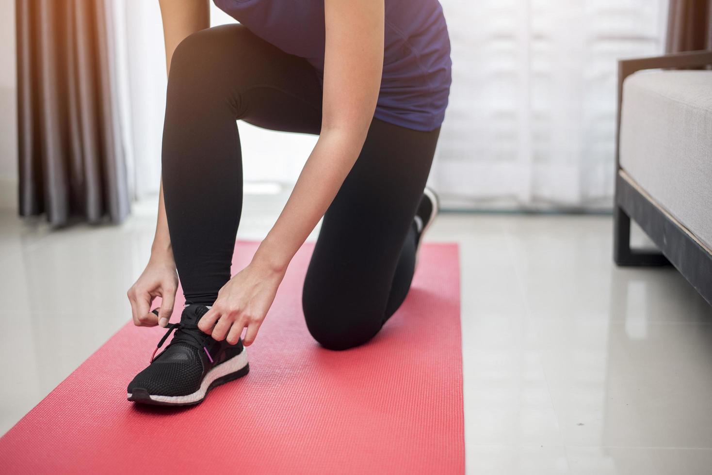 donna sportiva del primo piano che fa le scarpe allacciate foto