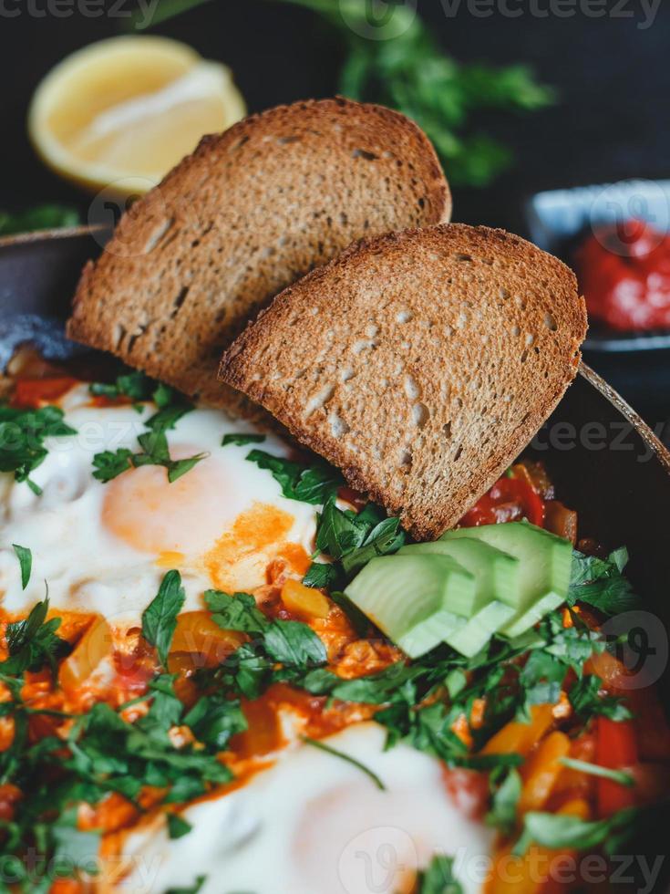 shakshuka con uova, pomodori, peperone e prezzemolo in padella. shakshuka è un cibo tradizionale israeliano. foto