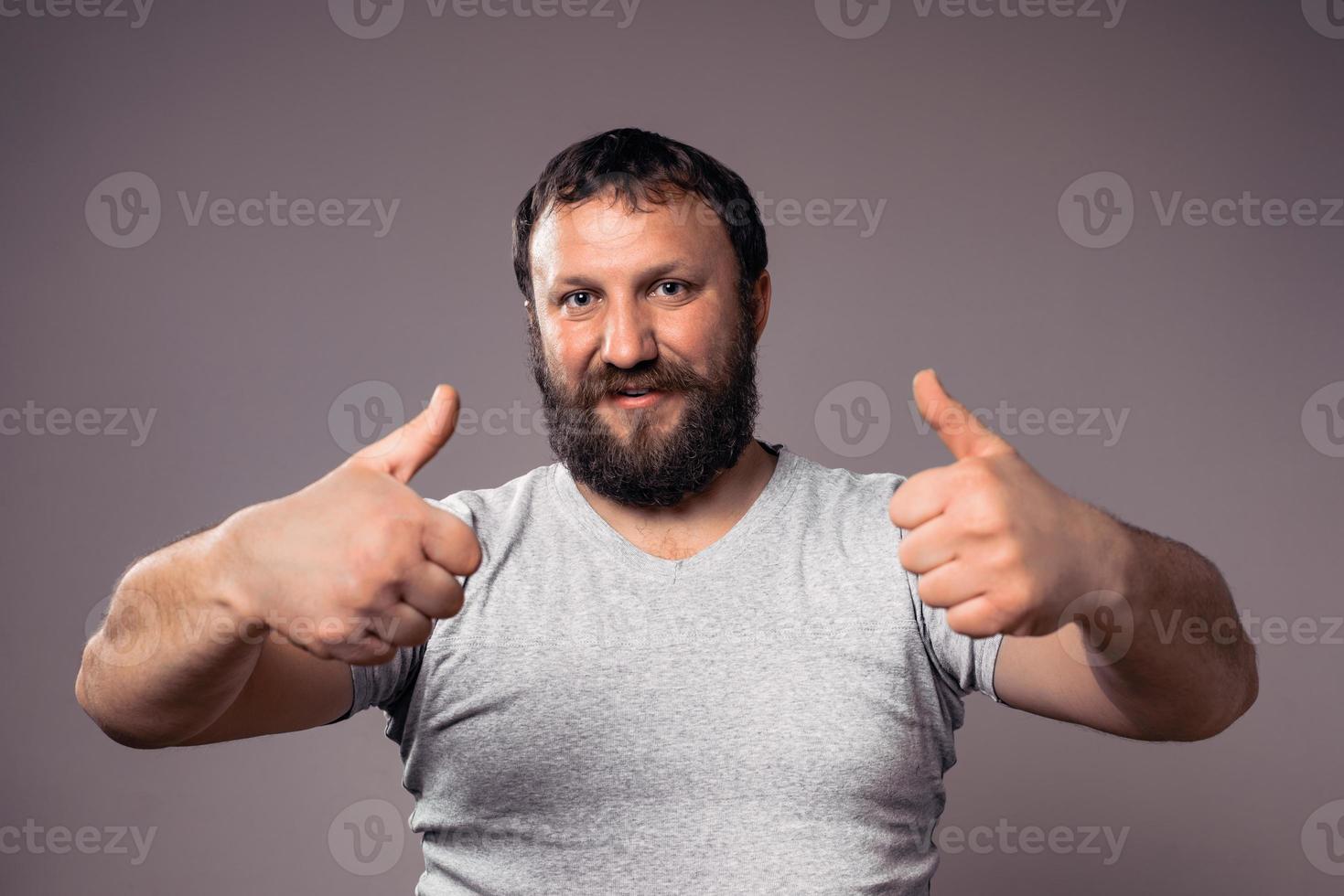 uomo barbuto eccitato bello felice in maglietta grigia con le mani in alto che celebra foto