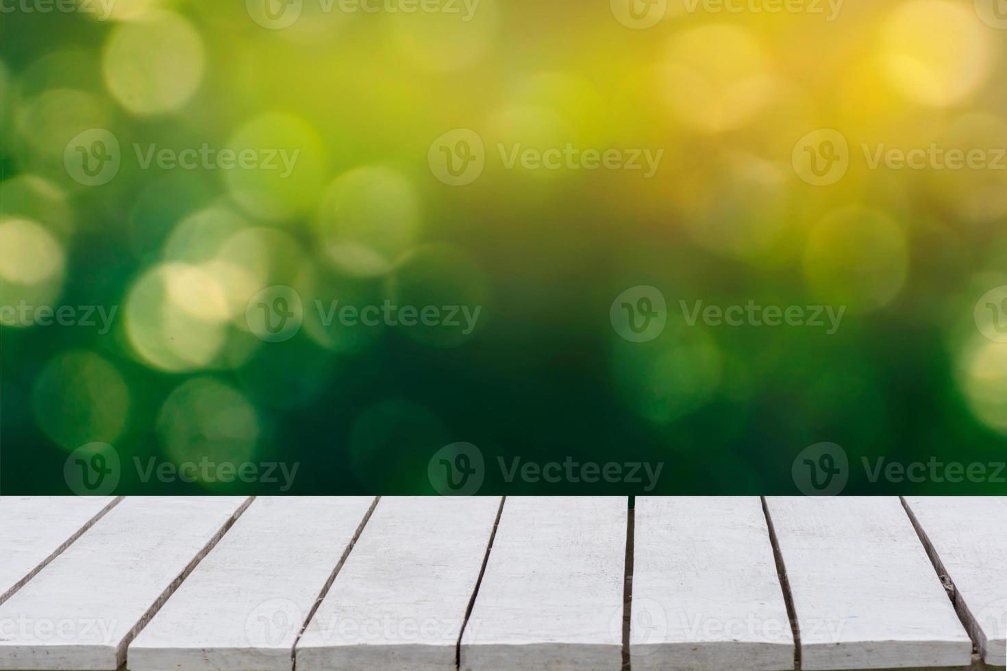 sfondo verde naturale con messa a fuoco selettiva. lo sfondo verde ha una foglia bokeh ed erba su un pavimento di legno bianco. foto