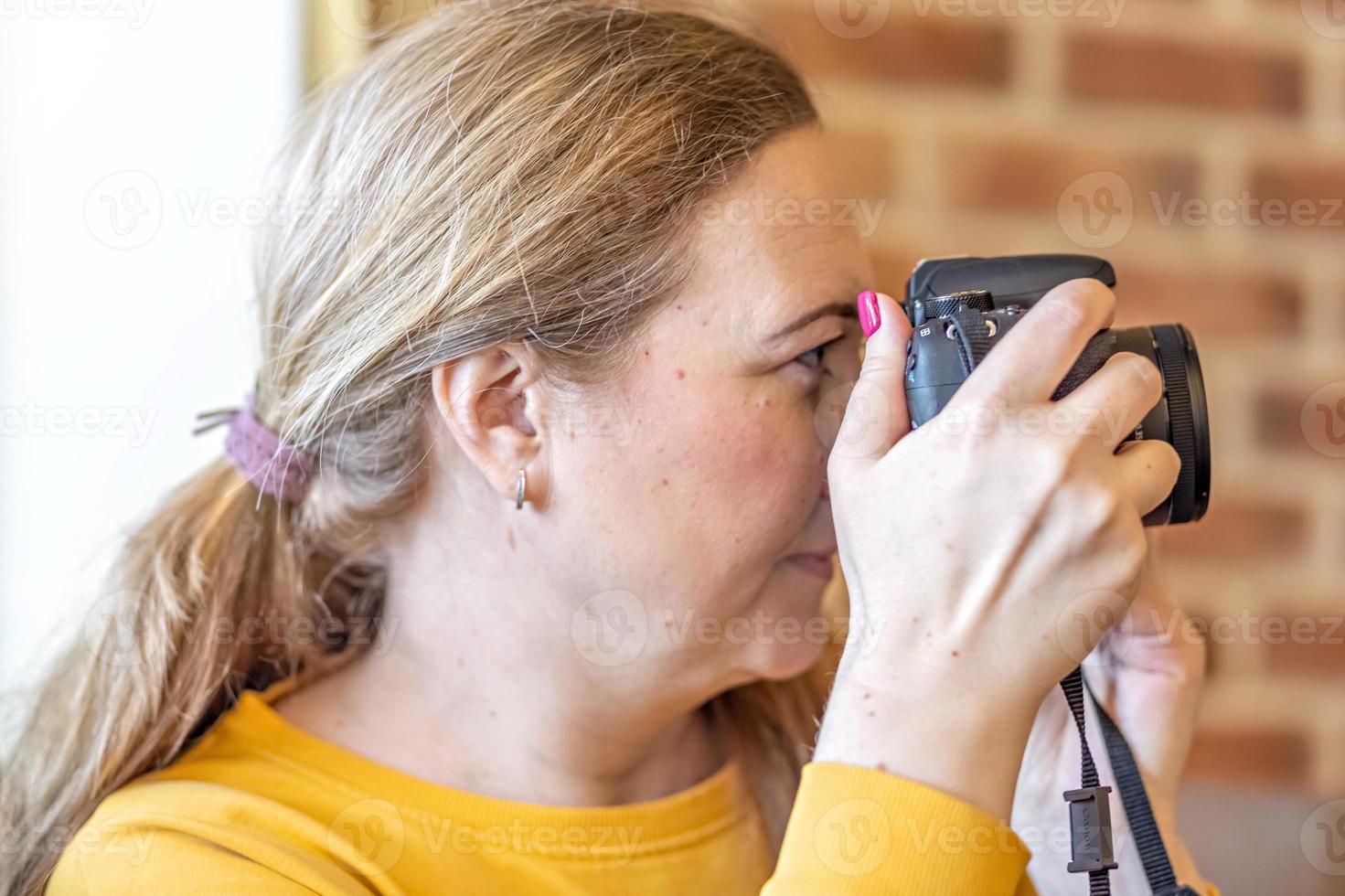 primo piano donna con una macchina fotografica in mano che scatta foto