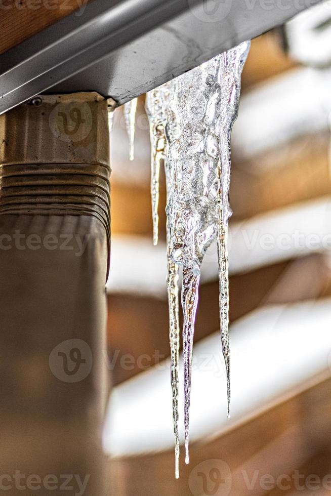 un grande ghiacciolo trasparente pende dal tetto della casa. gelate invernali foto