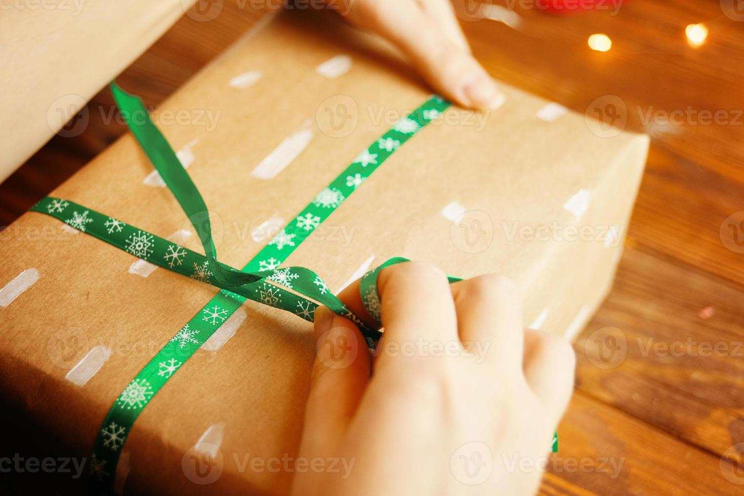 le mani delle donne che legano il nastro sul regalo di natale. foto