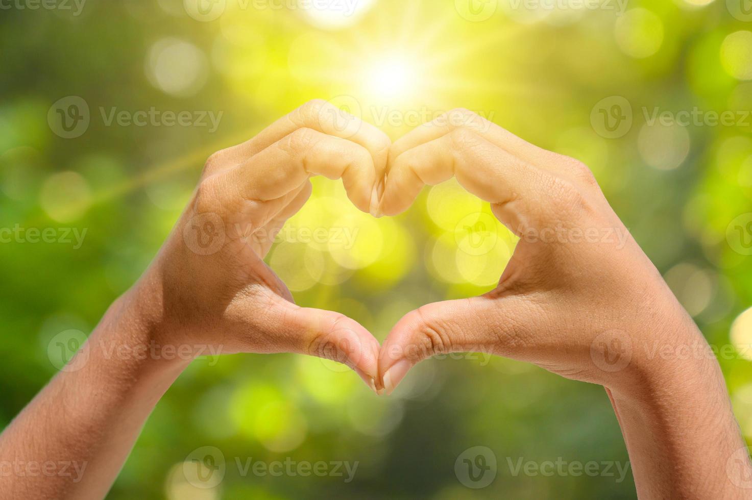 le mani delle donne e degli uomini sono a forma di cuore con la luce del sole che passa attraverso le mani foto