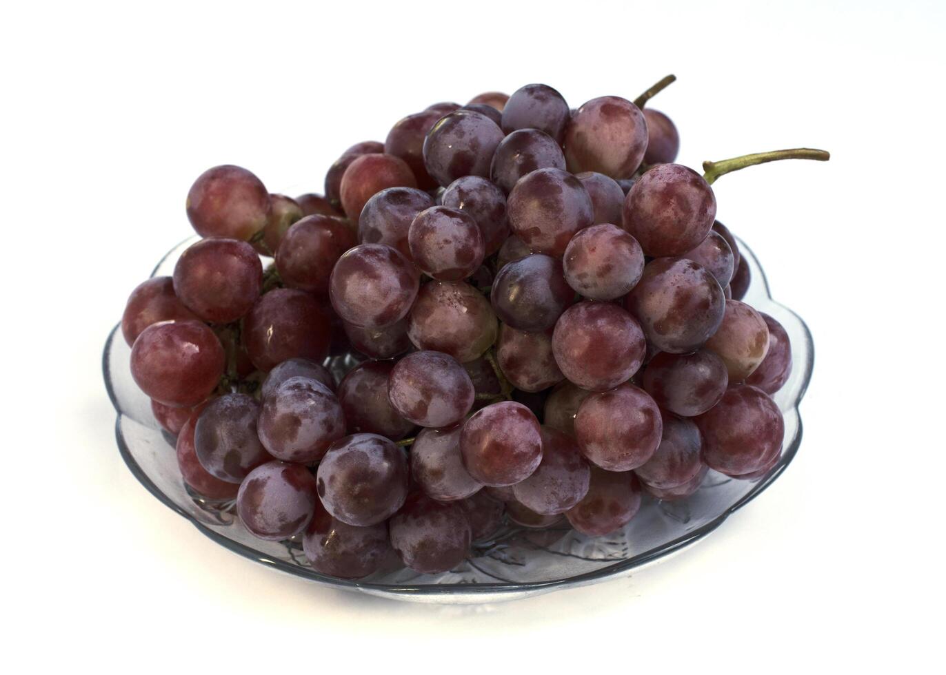 frutti di uva rossa sul piatto di vetro isolato su sfondo bianco foto