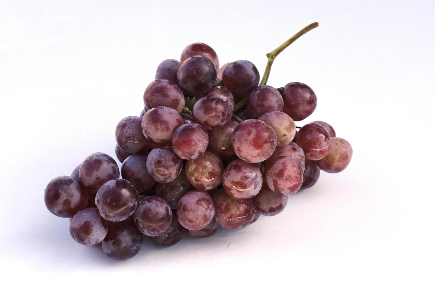 frutti di uva rossa sul piatto di vetro isolato su sfondo bianco foto