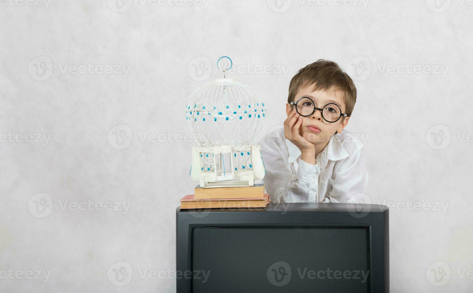 ragazzo di Sette anni vecchio sembra a bianca gabbia quale è allacciato su vecchio tv. foto