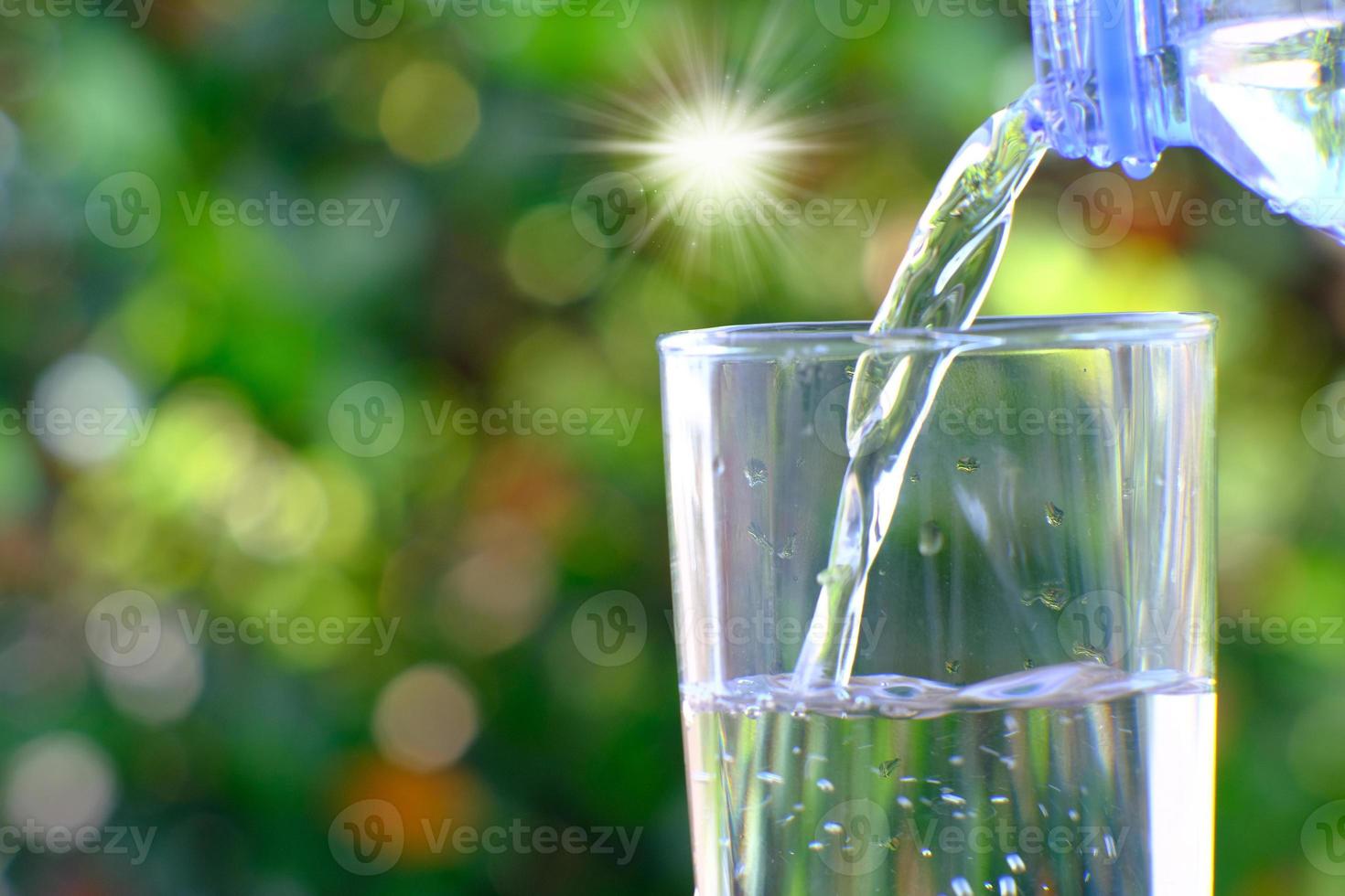 acqua dalla bottiglia che si versa in vetro su tavola di legno e concetto di assistenza sanitaria per acqua minerale, spazio per il testo foto