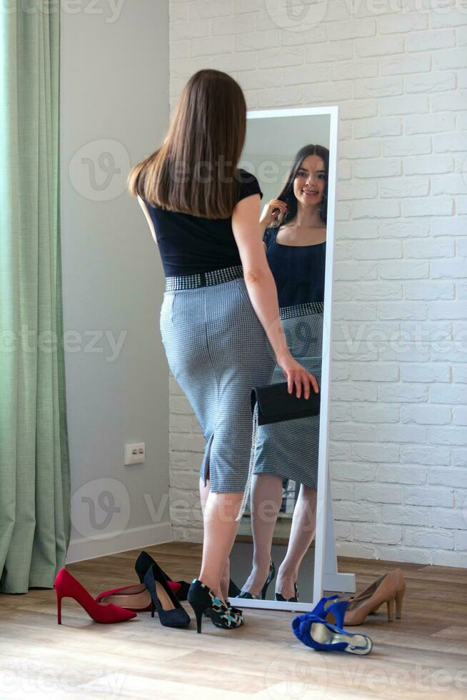 giovane donna guardare a sua riflessione nel il specchio, provando su scarpe foto