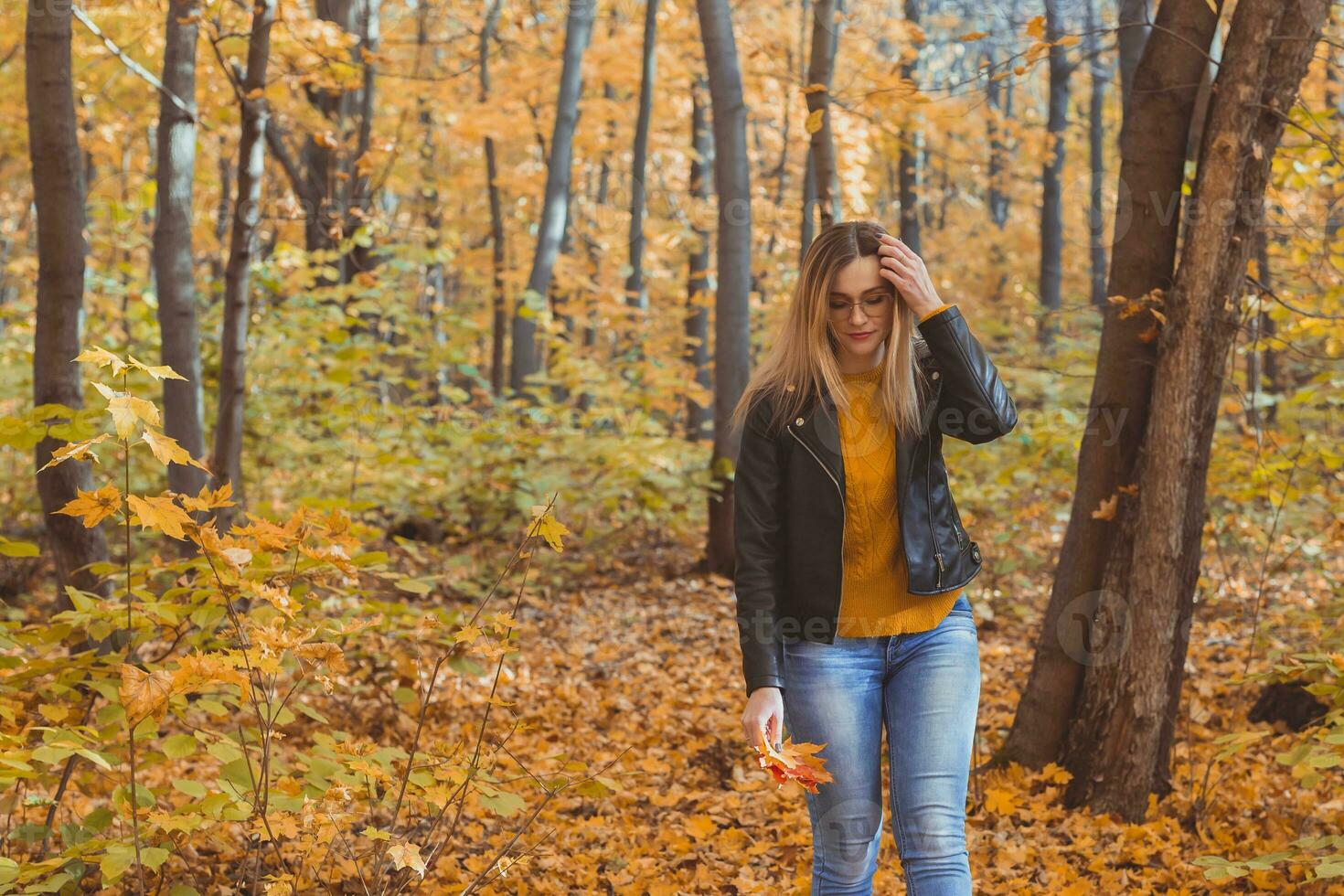 carino smiley donna Tenere autunno le foglie nel autunno parco. di stagione, stile di vita e tempo libero concetto. foto