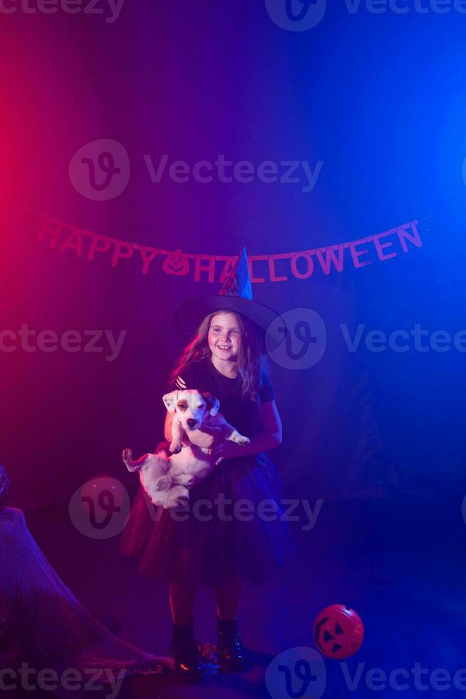 divertente bambino ragazza nel strega costume per Halloween con zucca Jack e cane. foto