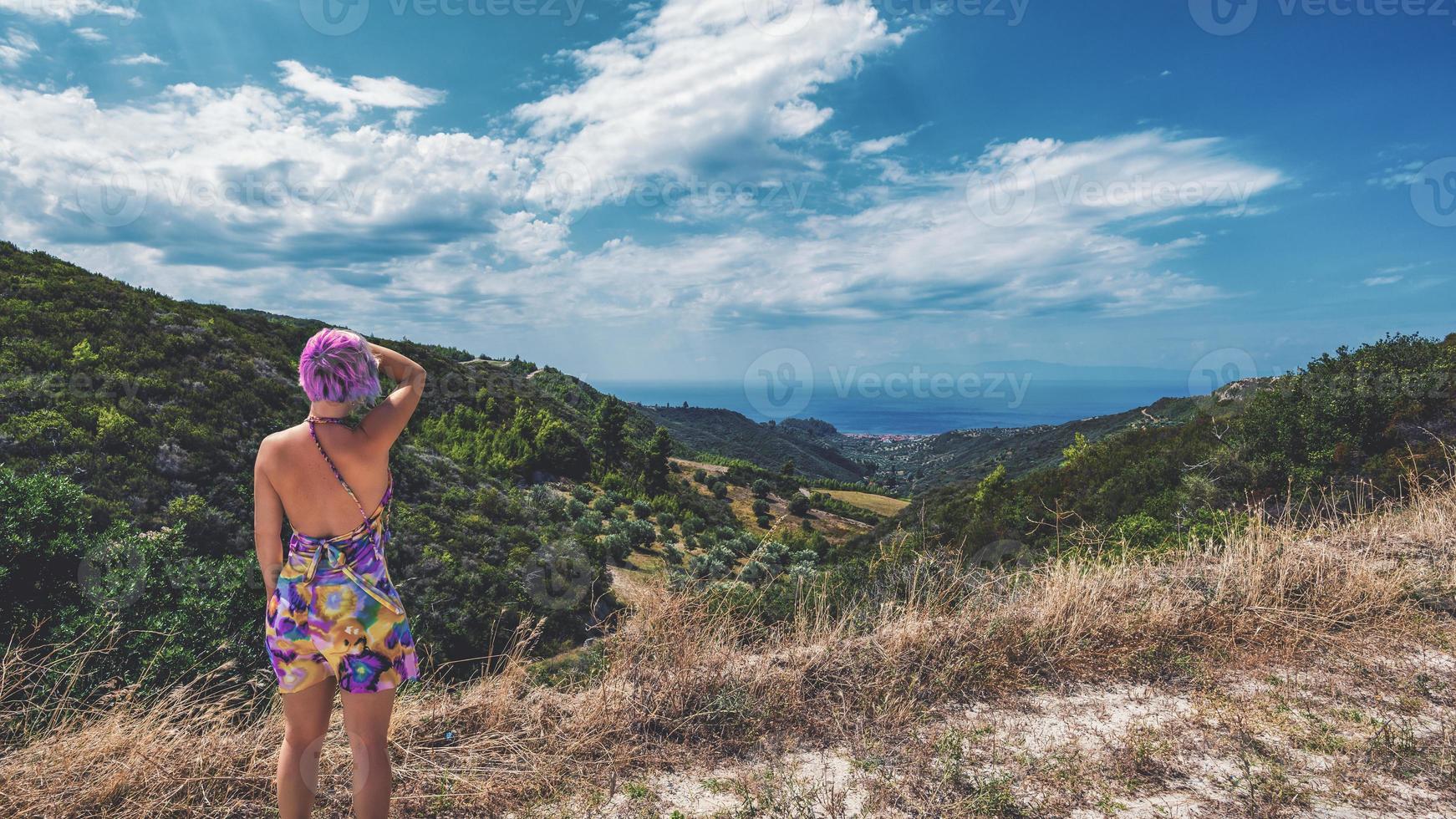 donna con il colore dei capelli rosa pazzo. donna con i capelli rosa che guarda la piccola città di nea skioni da uno dei punti più alti della penisola kassandra, in grecia. foto