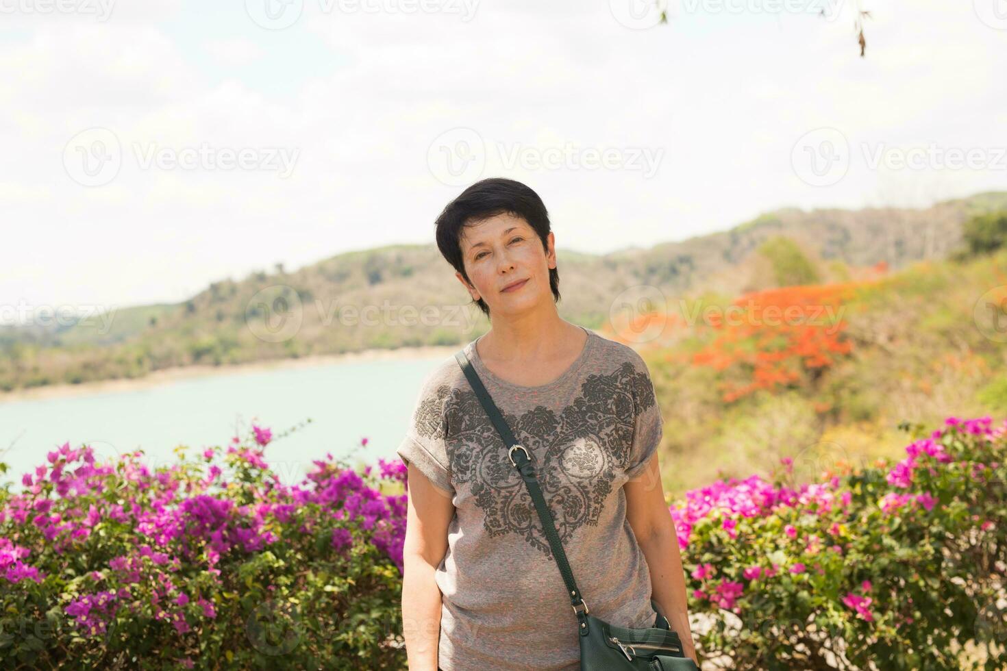 avvicinamento ritratto di bellissimo donna in piedi su il strada mentre guardare a telecamera e sorridente foto