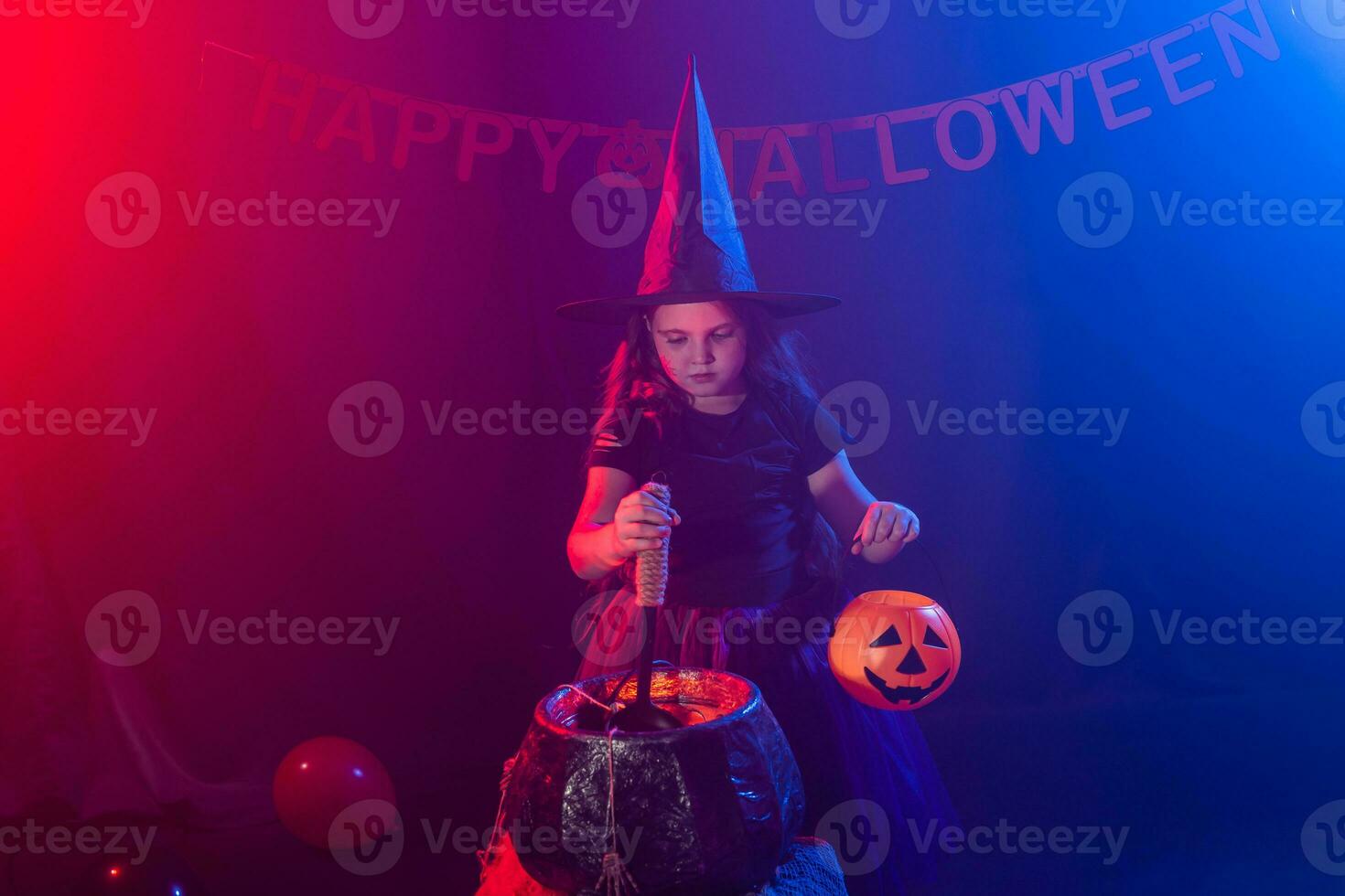 poco strega bambino cucinando pozione nel il calderone su Halloween. foto