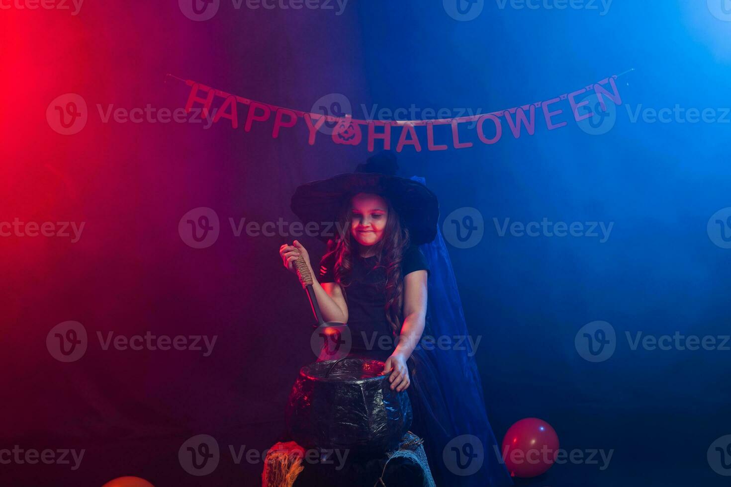 poco strega bambino cucinando pozione nel il calderone su Halloween. foto