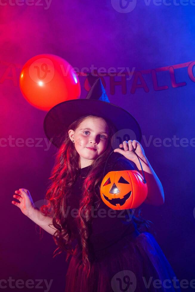 divertente bambino ragazza nel strega costume per Halloween con zucca Jack. foto