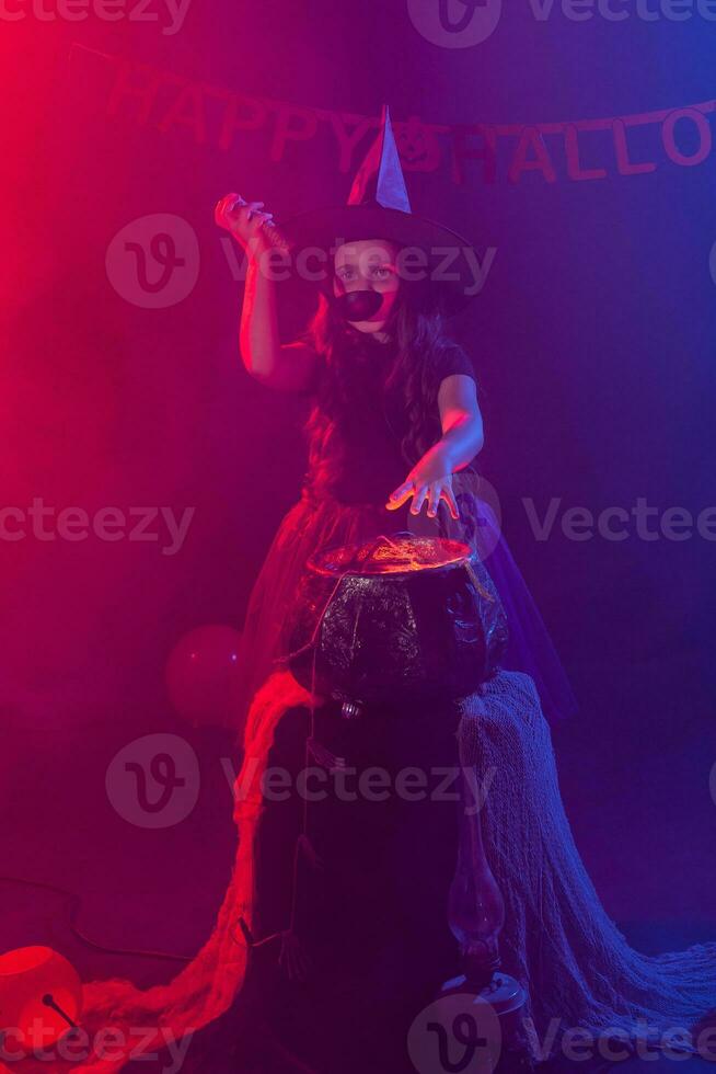 poco strega bambino cucinando pozione nel il calderone su Halloween. foto