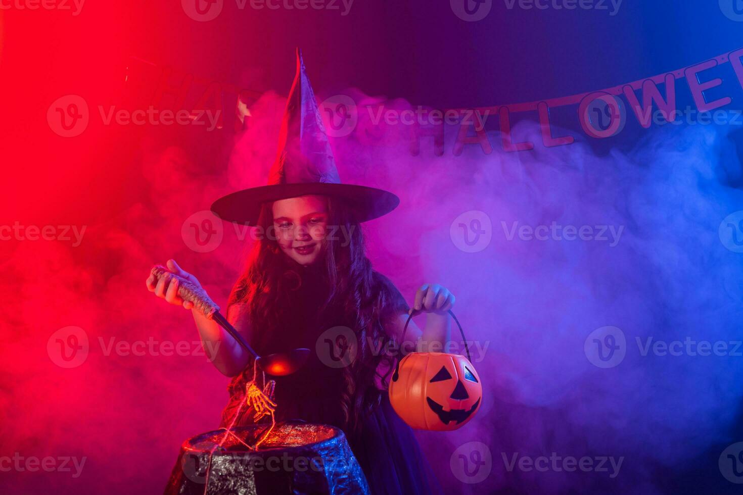 poco strega bambino cucinando pozione nel il calderone su Halloween. foto