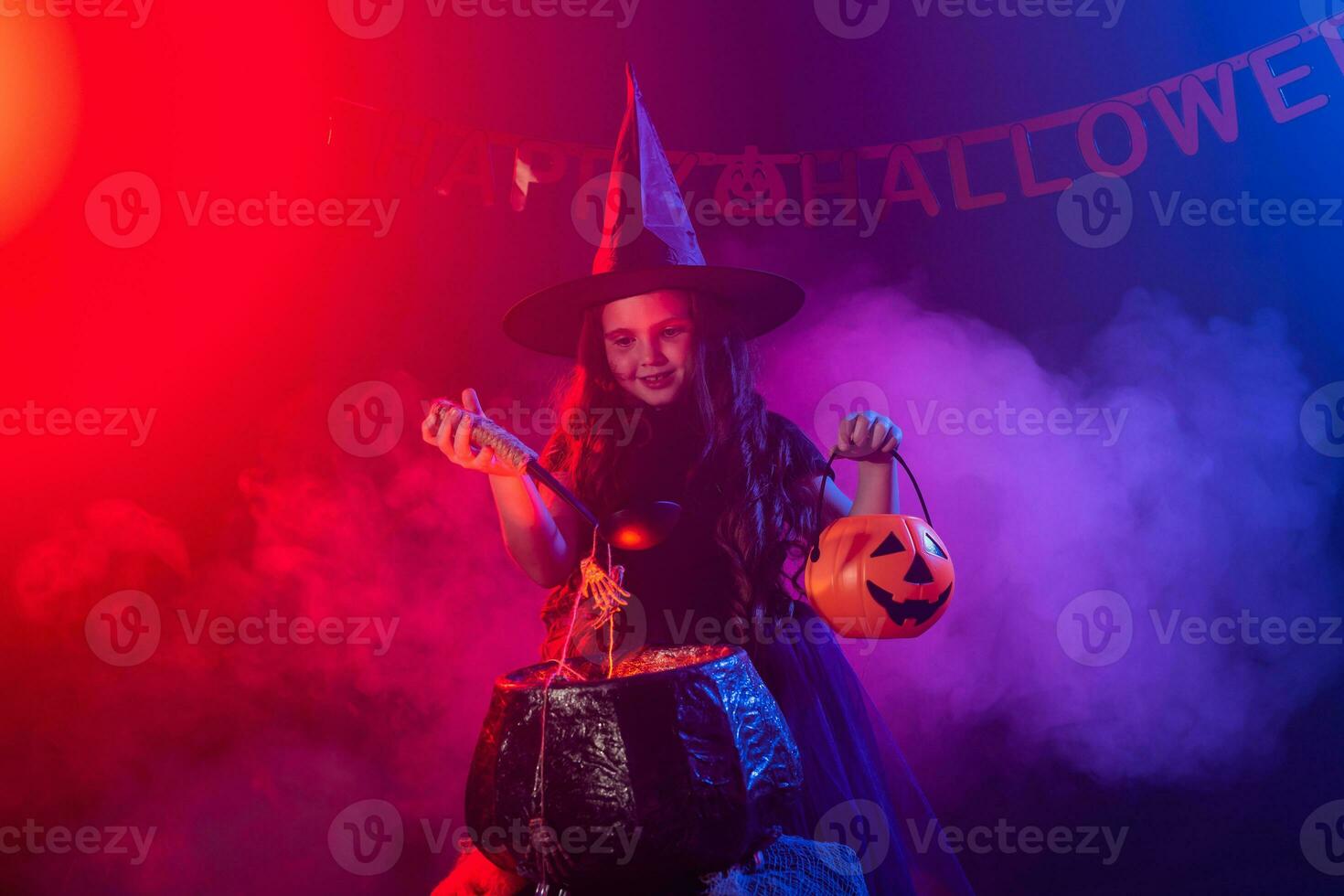 poco strega bambino cucinando pozione nel il calderone su Halloween. foto