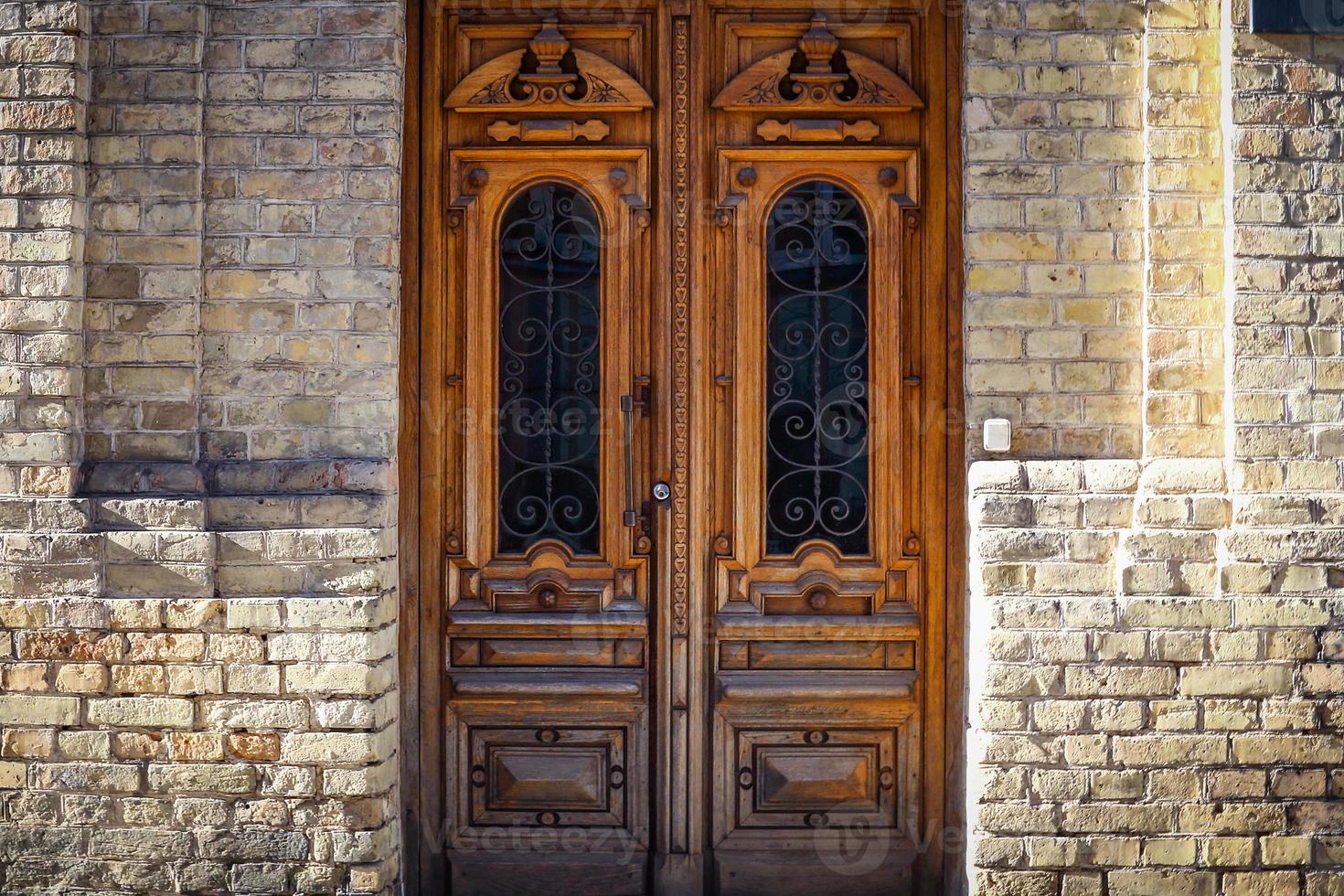 grande porta antica in legno marrone in un edificio con muro di mattoni foto