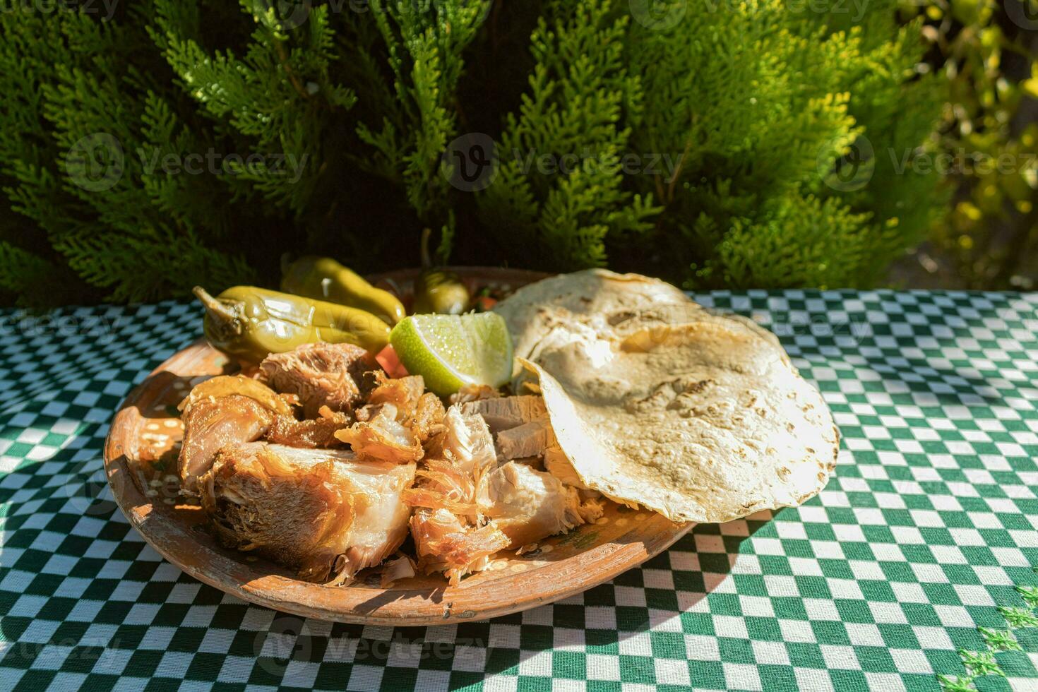 il messicano Carnitas piatto è servito su un' tavolo, ornato con vasellame e tovaglia foto