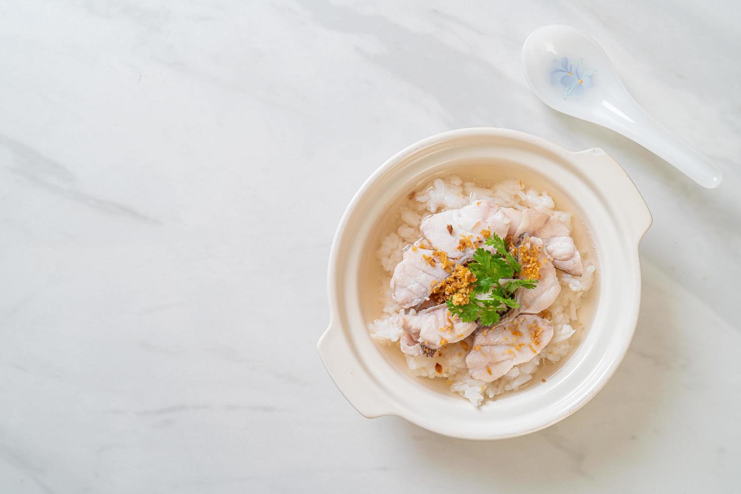 zuppa di porridge o riso bollito con scodella di pesce foto