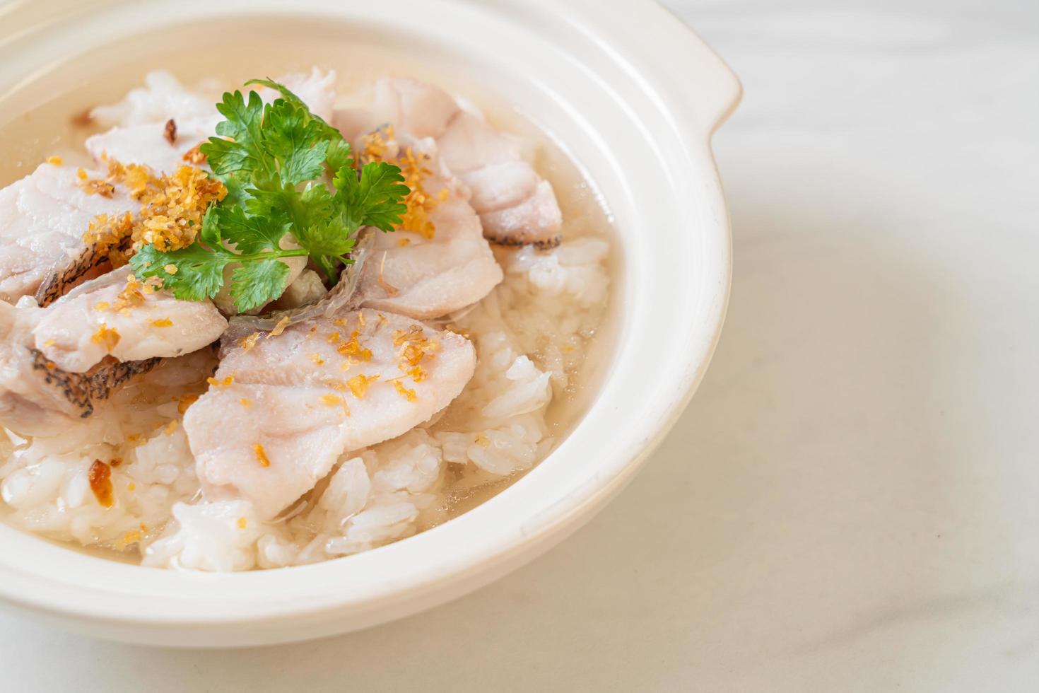 zuppa di porridge o riso bollito con scodella di pesce foto