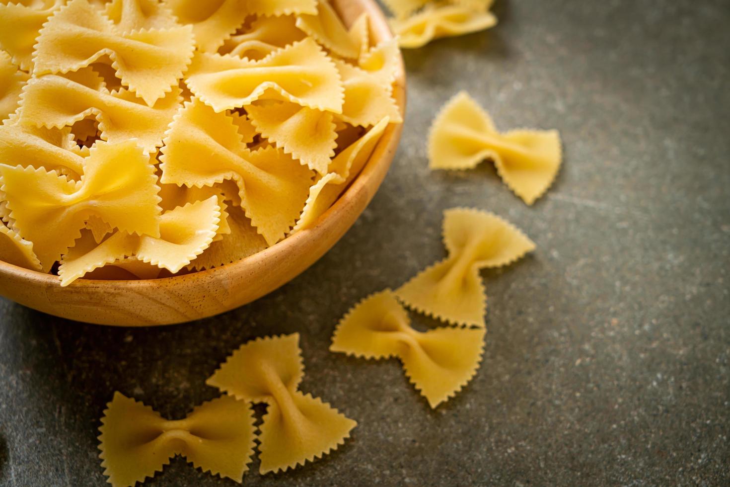 pasta secca di farfalle crude in una ciotola di legno wooden foto